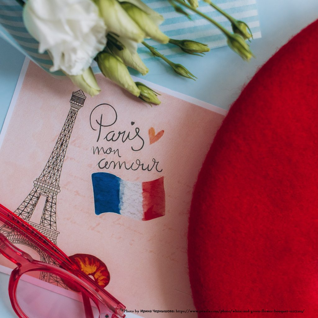 Promotional image French image with a postcard saying Paris mon amour, red glasses, a red beret and a white bouquet of flowers.